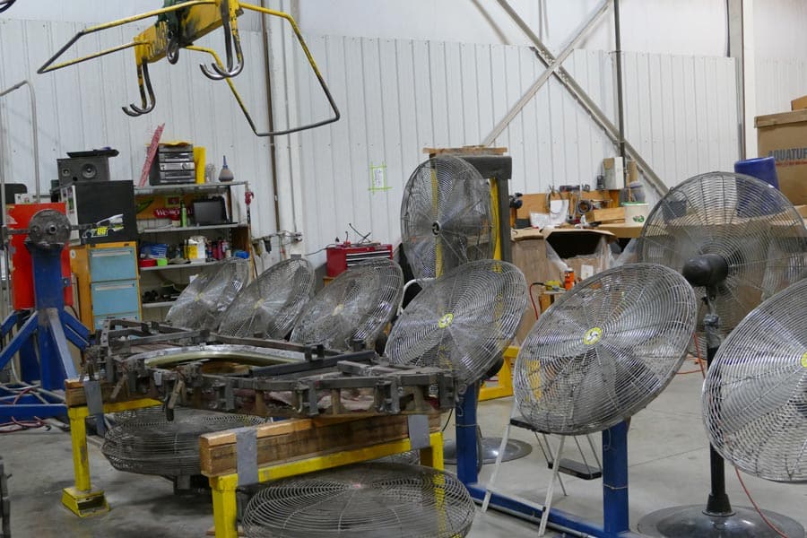 A row of fans that are used to cool kayak molds after they come out of the oven. 