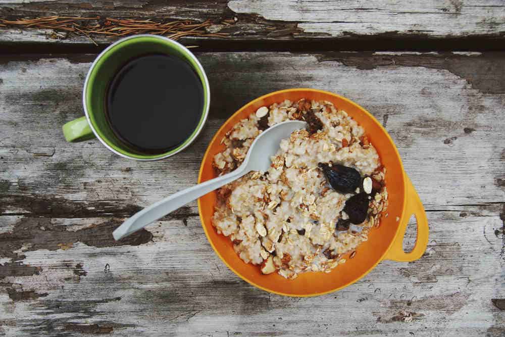 15 No-Cook Camping Breakfast Ideas (Perfect for Backpacking!) 1 Oatmeal on a picnic table with a cup of coffee.