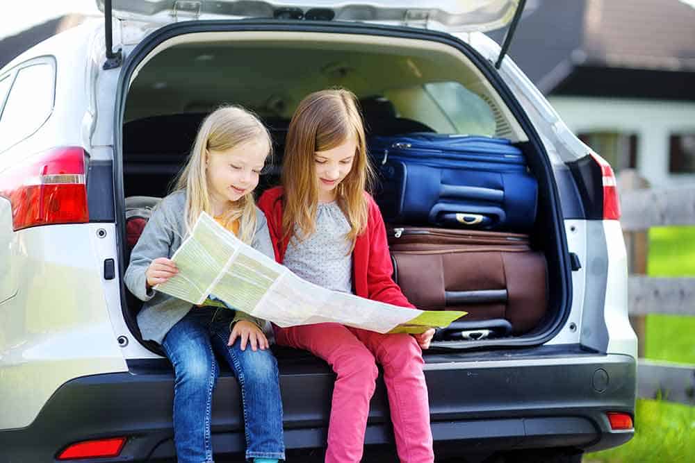 How to Plan The Perfect Family Camping Road Trip 1 Girls reading a map in the back of a car.