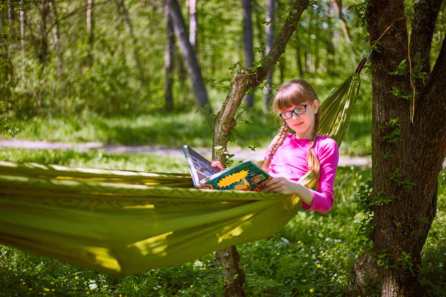 Young Girl Reading in Camping Hammock