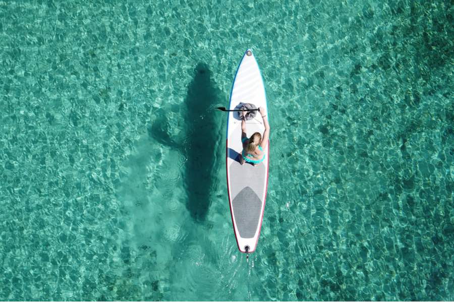 Ultimate Beginner’s Guide to Stand Up Paddleboarding (SUP) 2 Bird's Eye View of Woman SUPing on Clear Blue Water