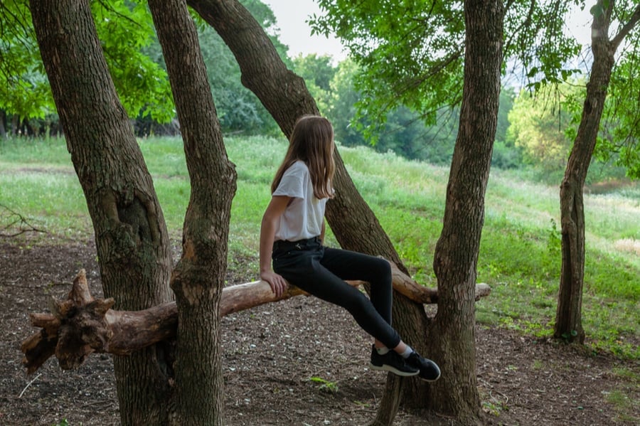 Girl Sitting On Log in Woods