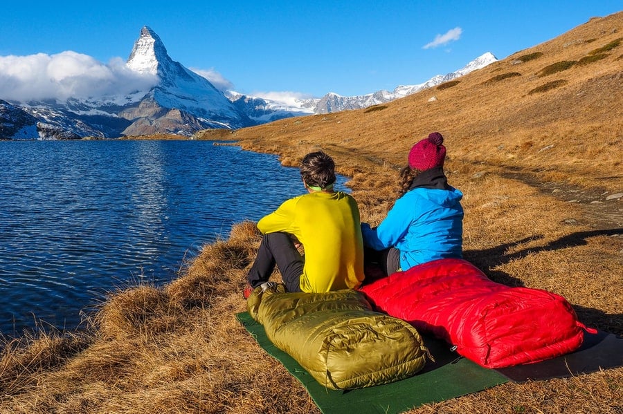 How To Choose A Sleeping Bag 1 people sitting in sleeping bags looking at a lake