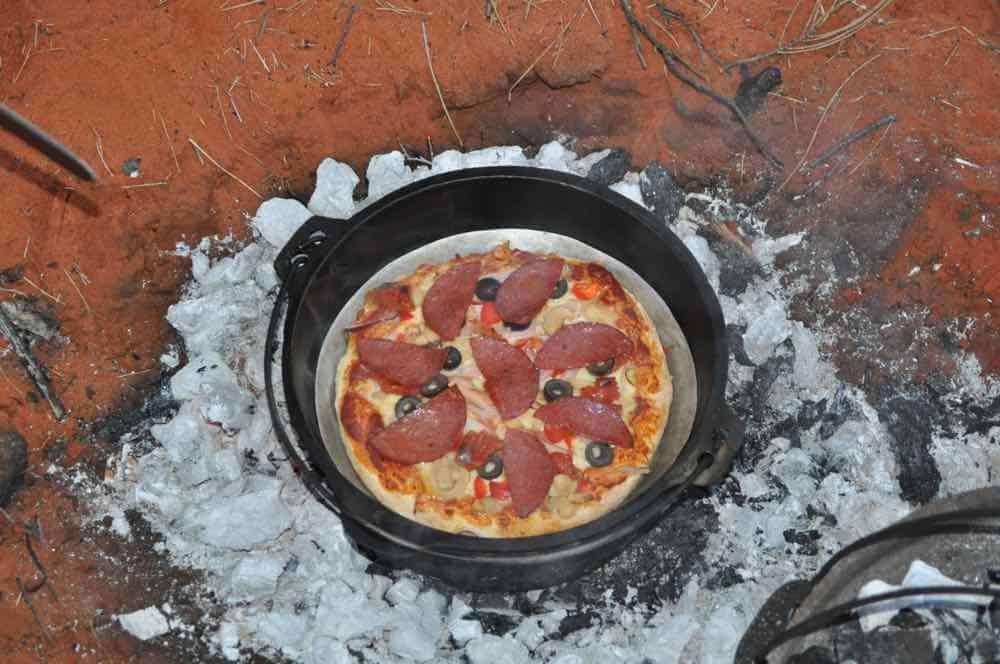 35 Easy Dutch Oven Camping Recipes 4 Cooking a pizza in a dutch oven over campfire coals.