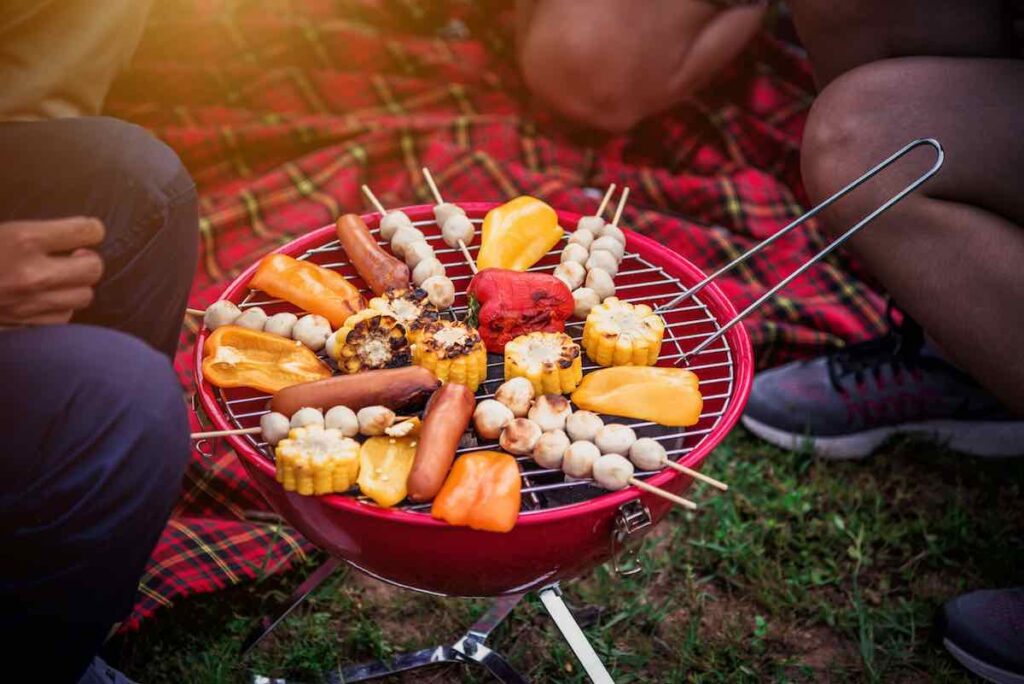 The Complete Camping Food Checklist for First-Time Campers 11 Grilling skewers of food on a small charcoal grill.