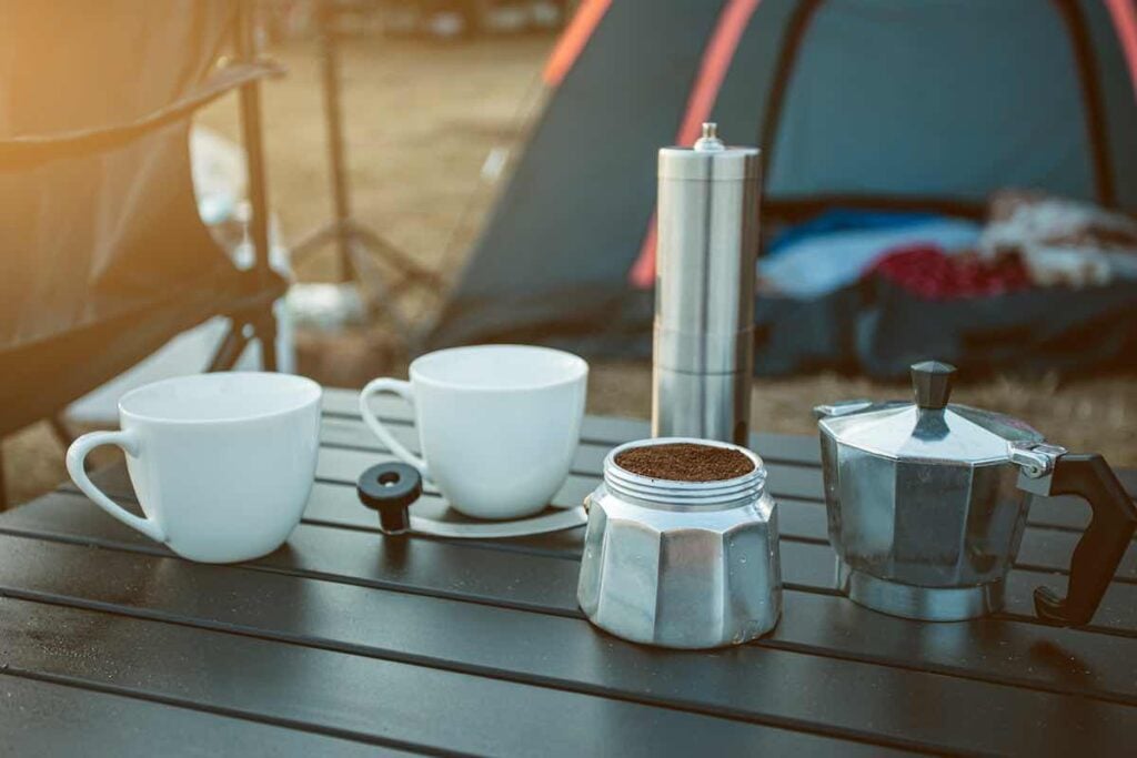 A camping table laid out for morning coffee. Tent Camping Essentials.