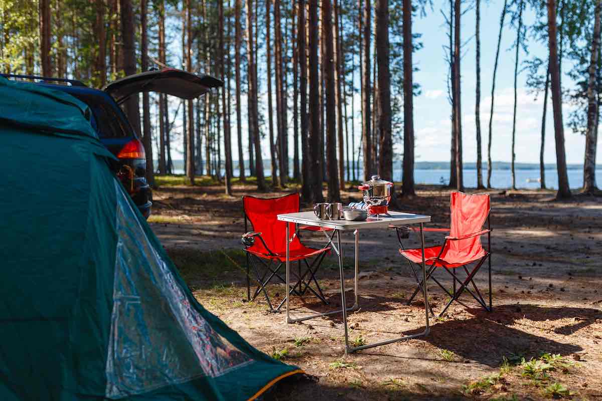 18 Camping Essentials for a Stress-Free Outing 6 A table and camping chairs set up at a campsite.