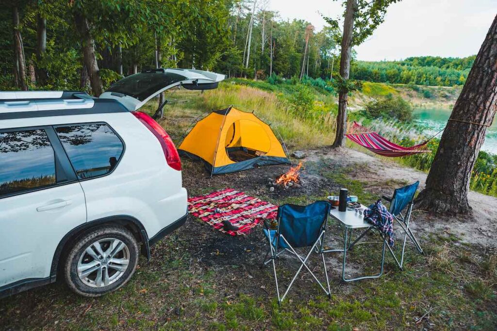 A small campsite set up, with the car parked nearby.