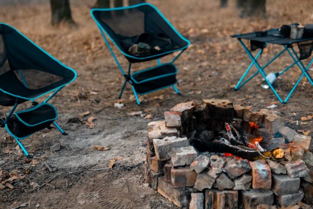 Camping chairs set up around a campfire.