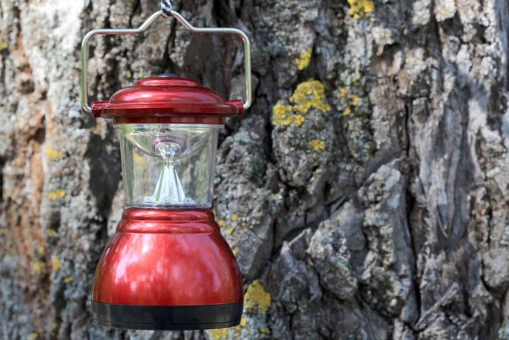 Lighting Up the Night: The Top 5 Best Solar Lights for Camping 7 A camping lantern hanging near a tree.