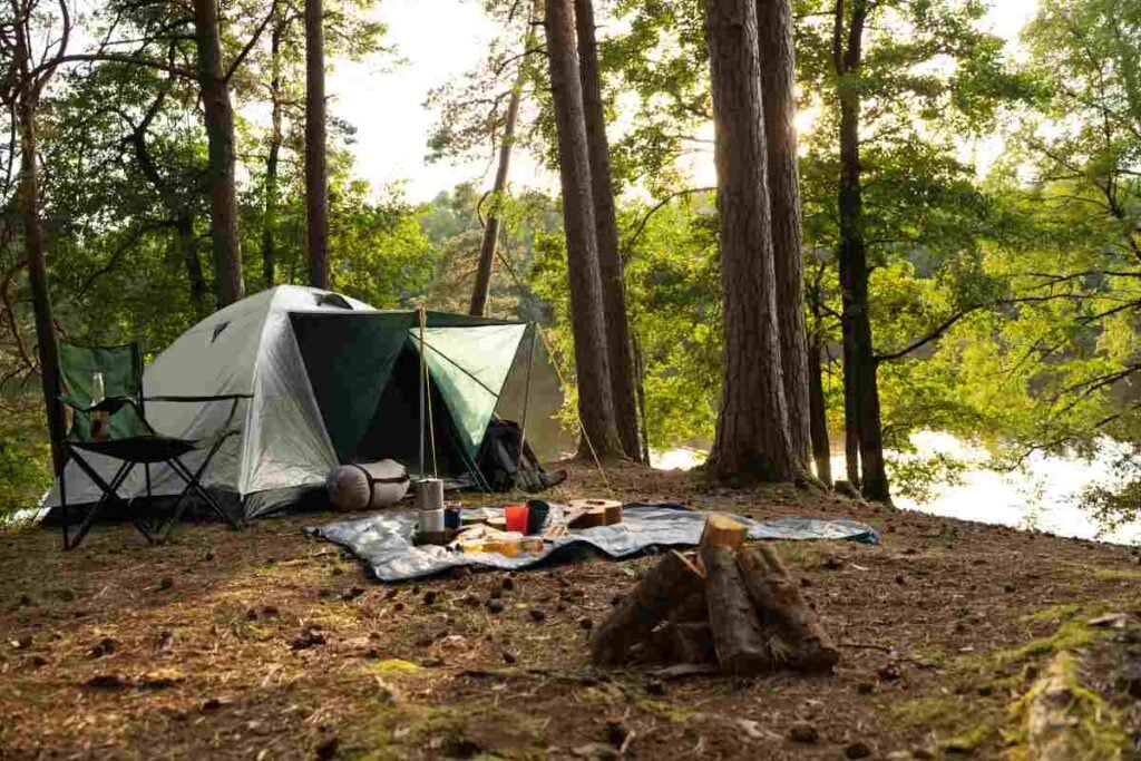 A tent campsite set up in a wooded setting near water.