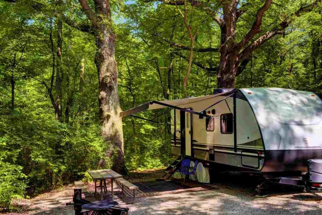 An RV set up at a wooded campsite.