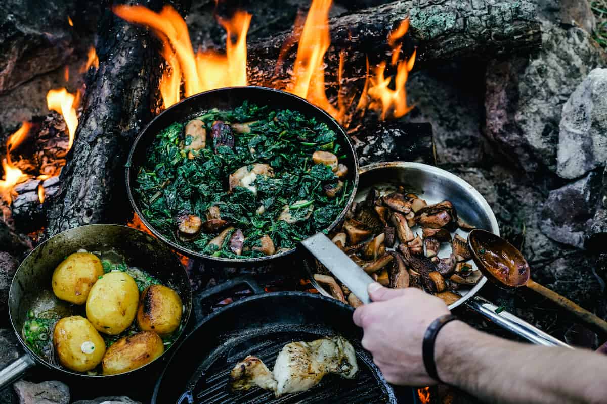 18 Camping Essentials for a Stress-Free Outing 4 Preparing a meal over a campfire.