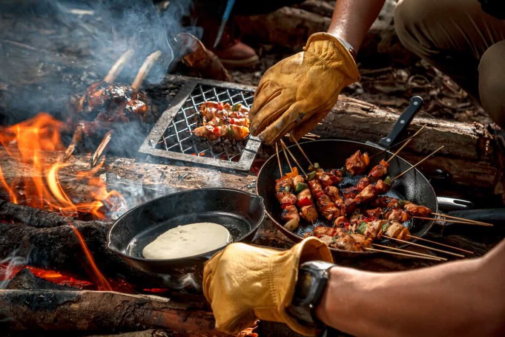 Using skillets and skewers to cook over a campfire.