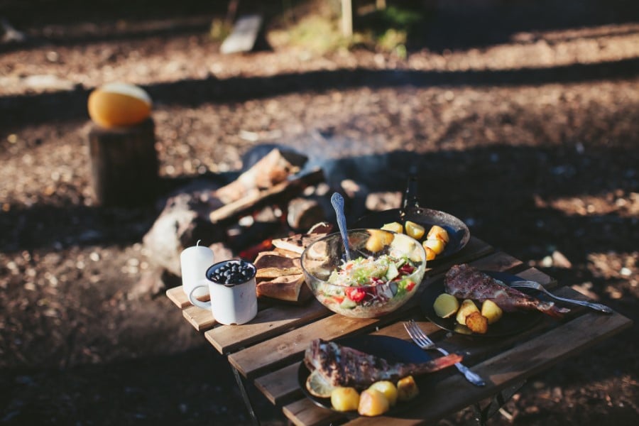 The Complete Camping Food Checklist for First-Time Campers 10 A grilled camping meal set on a small camping table.