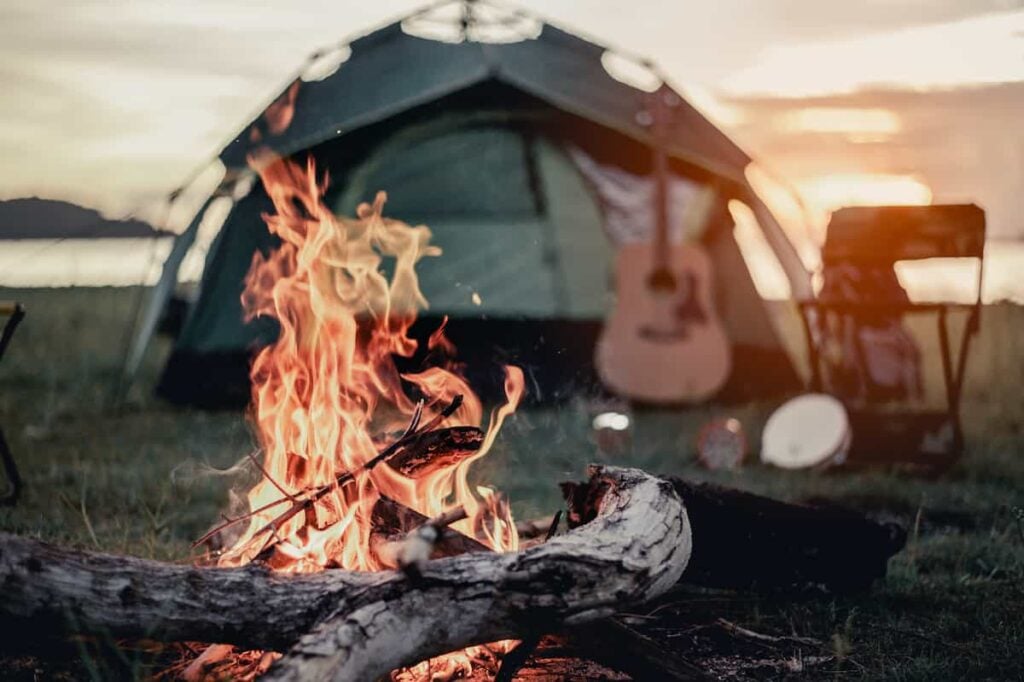 Sunset over a tent campsite set up on a beach.