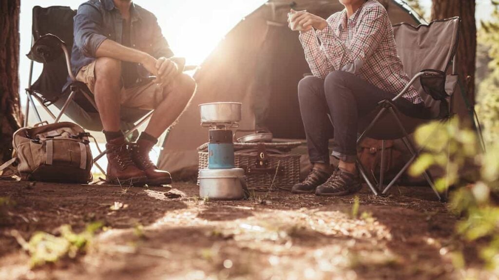 Cropped photo of a man and woman couple sitting in camping chairs at a campsite.