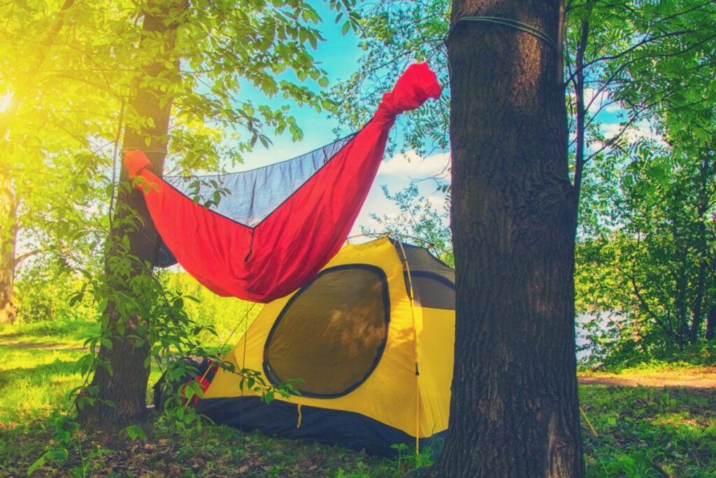 A hammock handing near a tent.