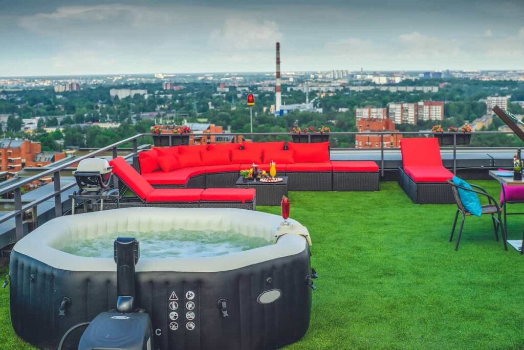 An inflatable hot tub on an outdoor rooftop deck with color-coordinated patio furniture nearby.