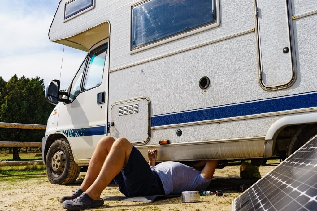 Man inspecting the underside of an RV motorhome.