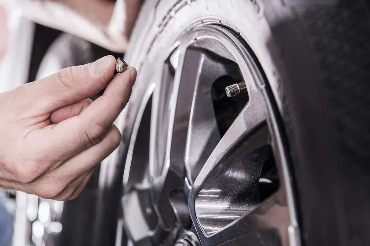How to Dewinterize Your RV: Everything You Need to Know 7 Man holding tire valve cap for an RV tire.