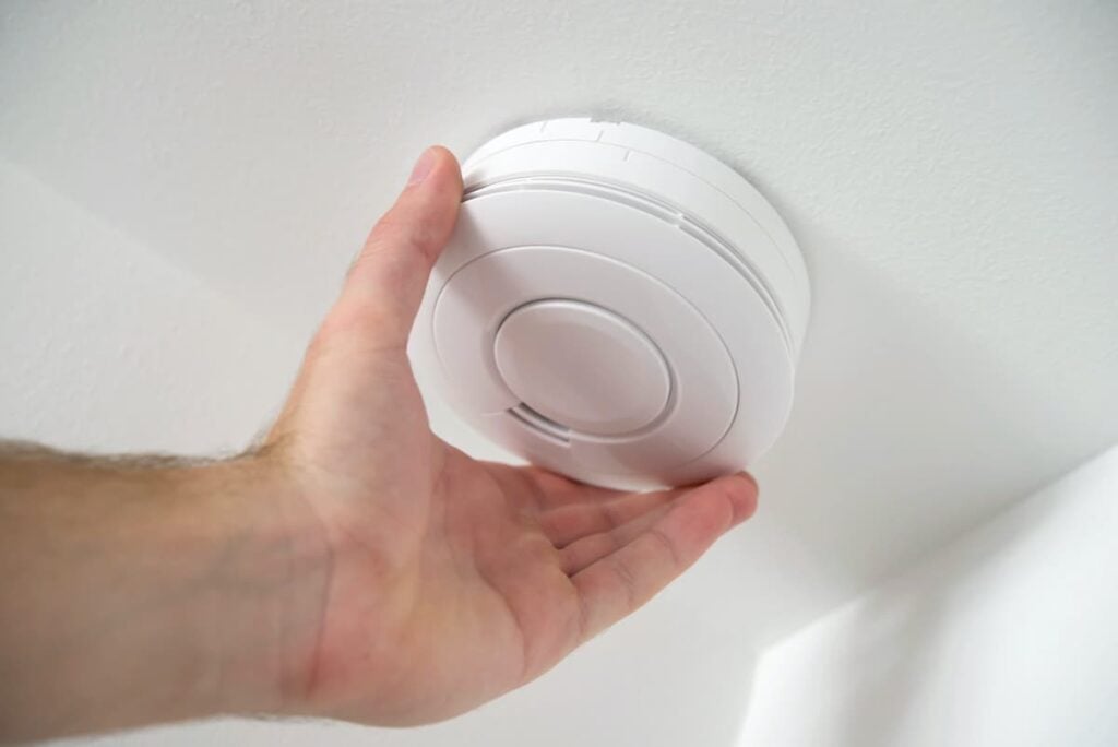 Man checking a ceiling smoke detector.