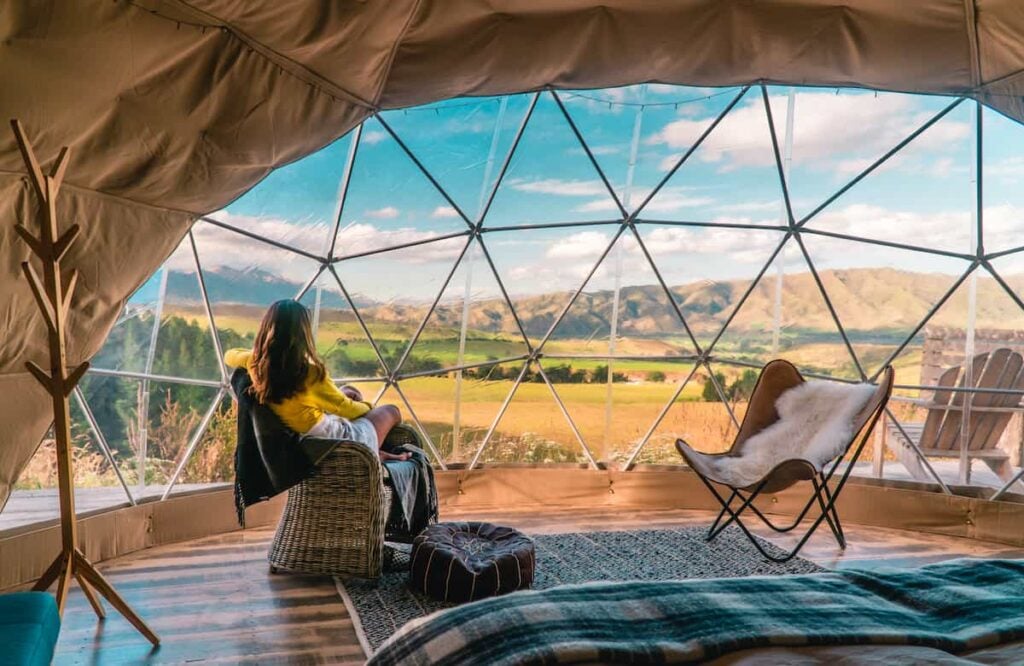 A woman enjoying a view from in the interior of a glamping dome.