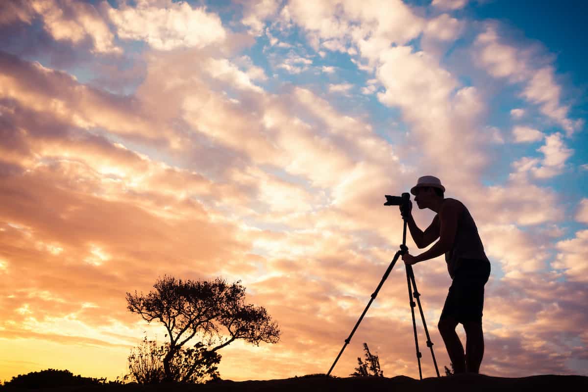 Travel Photography: Tips and Tricks for Stunning Images 9 A man using a camera either just before sunrise or just after sunset.