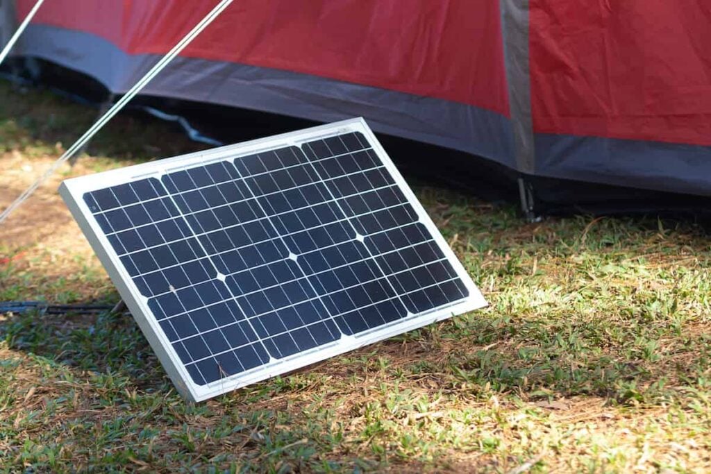 Portable solar camping panels set up next to a tent.