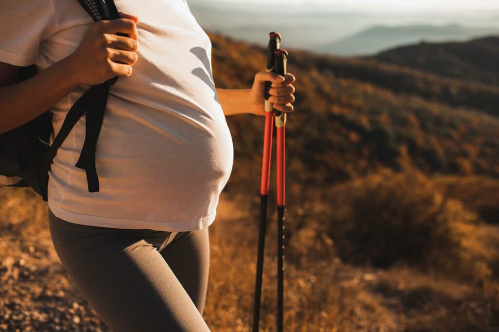 A pregnant woman on a hike. Camping while pregnant can be safe and enjoyable with the right planning.