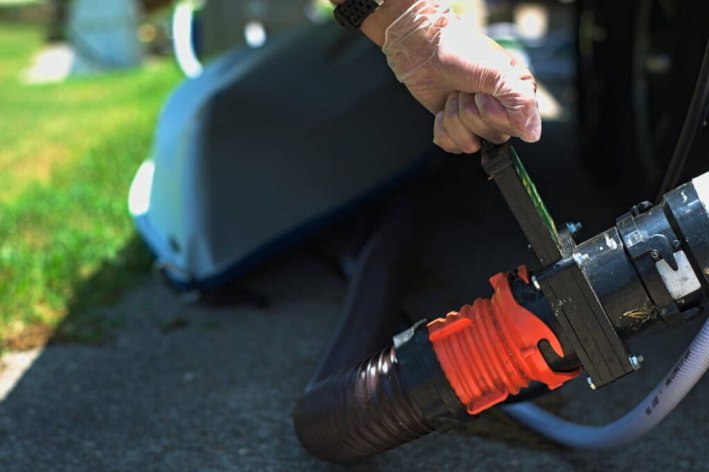 Person using sewer hose to drain RV waste tank.