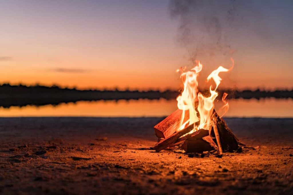 How to Put Out a Campfire 1 A campfire at night near water. How to put out a campfire.