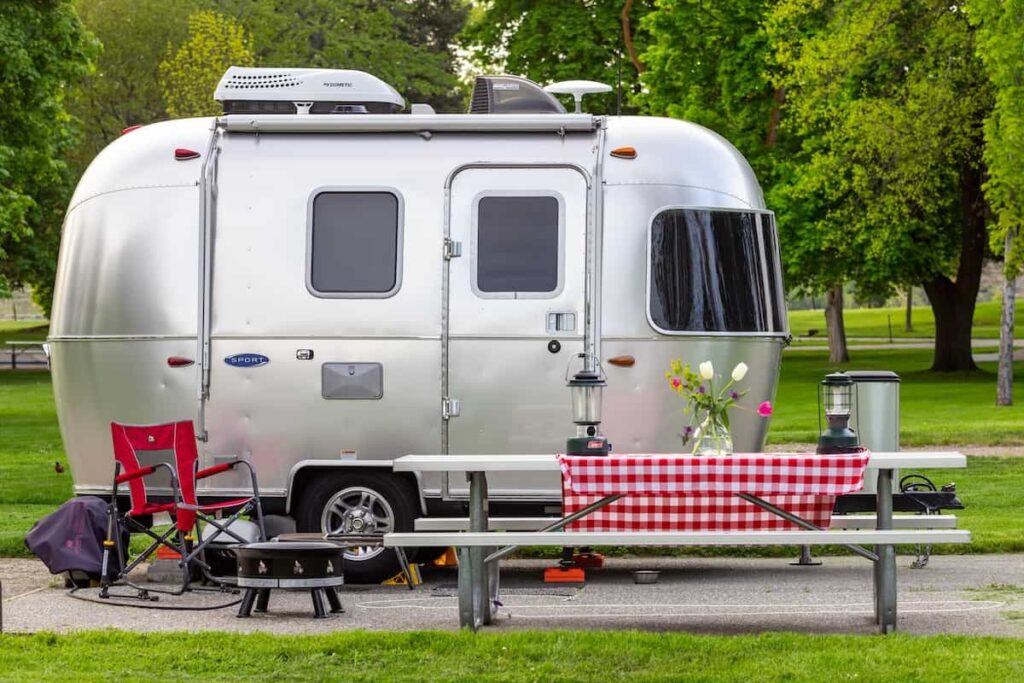 A vintage-style camper trailer at a campground.