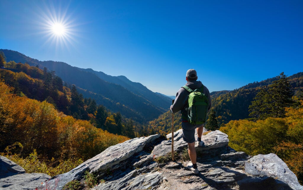 Man relaxing on autumn hiking trip. Man hiker  sitting on top of the mountain enjoying beautiful fall scenery. Smoky Mountains National Park, near Gatlinburg, Tennessee, USA