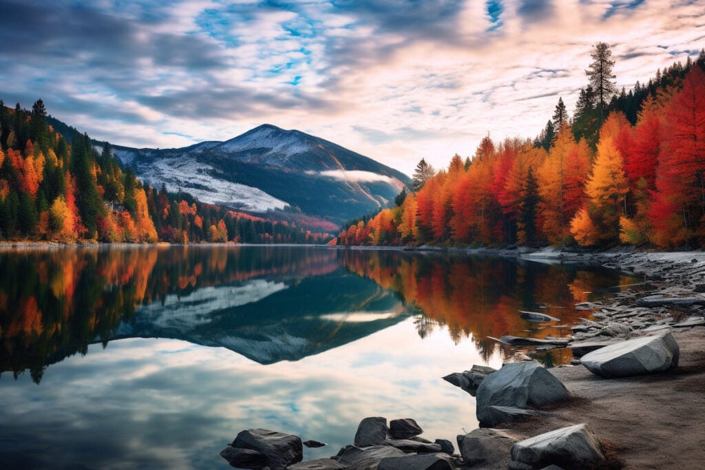 A serene mountain landscape with snow-capped peaks piercing through the clouds, a tranquil alpine lake reflecting the vibrant colors of the surrounding autumn foliage. High quality photo